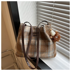 Close-up of vintage plaid wool tote bag with leather straps and plush animal charm