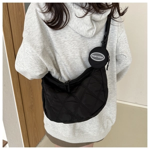 Detail of black quilted shoulder bag featuring a detachable round coin purse on the strap