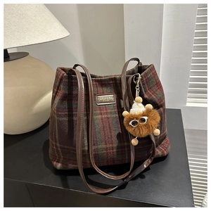 Detailed view of vintage wool plaid bucket bag with leather handle and plush charm