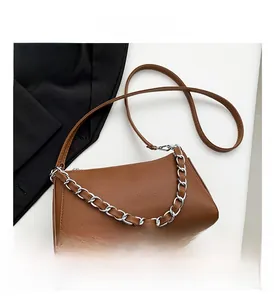 Detail of brown litchi pattern leather baguette bag with silver chain and zipper