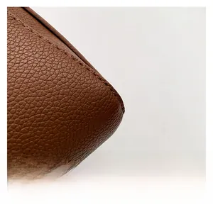 Close-up of premium brown litchi grain leather texture and neat stitching on small square bag