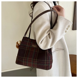 Detail of wool plaid bucket bag with vintage leather tag and cute plush bear charm