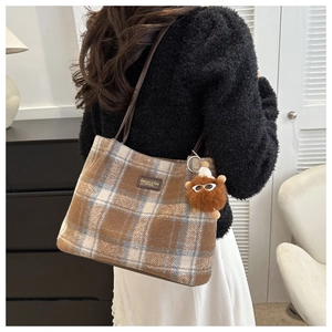 Detail of wool bucket bag featuring vintage plaid pattern and brown plush ball charm