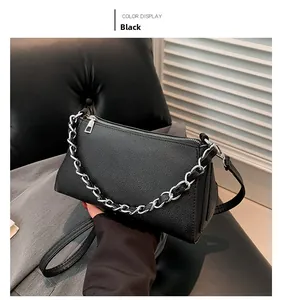 Detail of black litchi texture leather handbag with silver chain and zip closure