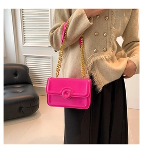 Detail of rose pink crossbody bag with gold chain strap shown on model's shoulder