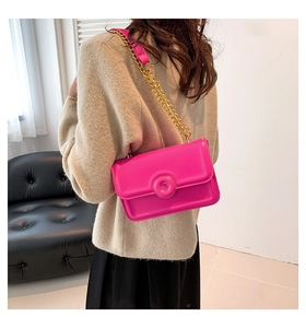 Detail of rose pink rectangular shoulder bag with chunky gold chain strap and metal clasp