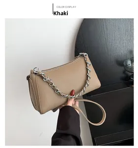 Detail of khaki lychee grain leather bag with decorative thick silver metal chain link