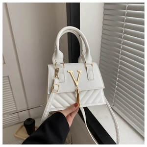 Détail du sac blanc en similicuir matelassé avec logo V doré, pompon et poignée haute