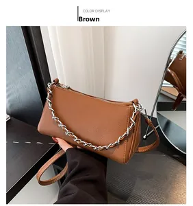 Detail of brown litchi texture handbag featuring silver chain strap and top metal zipper