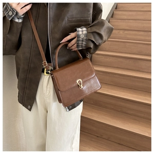 Close-up of vintage brown PU leather crossbody bag with elegant gold metal clasp