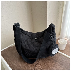 Detalle del bolso bandolera acolchado negro con patrón de rombos y monedero redondo