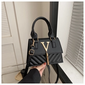 Détails du sac matelassé noir avec boucle en V dorée et pompon métallique élégant