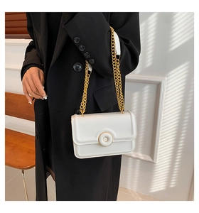 Chic white crossbody bag with large round gold buckle and chain strap on black blazer