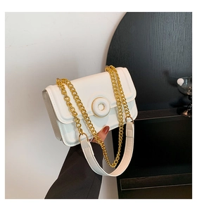 Detail of white leather shoulder bag with gold chain strap and circular buckle accent