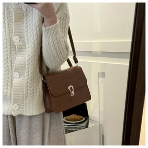 Close-up of brown vintage square crossbody bag with a gold metal clasp and adjustable strap