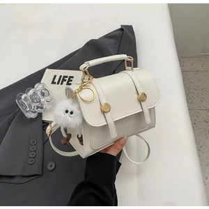 Witte vintage vierkante crossbody tas met leren riemen en een pluizige monster hanger
