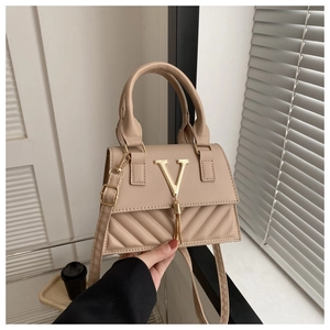 Détail du sac à main beige avec logo V doré, gland décoratif et motif matelassé en V