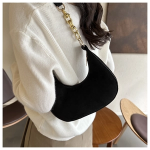 Detail of black crescent suede shoulder bag featuring a chunky gold metal chain strap