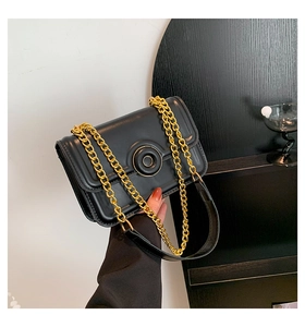 Detailed close-up of a black leather shoulder bag with a gold circular buckle and chain strap
