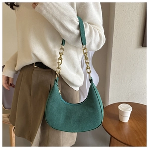 Detail of forest green suede hobo bag with a gold chain strap and vintage saddle design