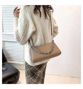 Detail of khaki leather crossbody bag with silver chain strap on autumn outfit