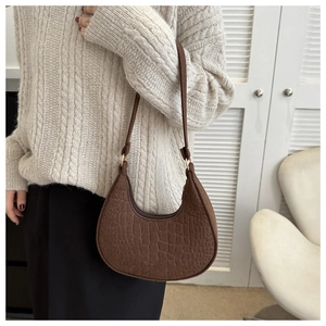 Close-up of vintage brown crocodile texture hobo bag worn with a knit sweater