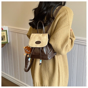 Detailed back view of a retro color-block backpack with drawstring and plush pendant