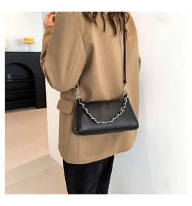 Close-up of black litchi grain leather crossbody bag with silver thick chain decoration