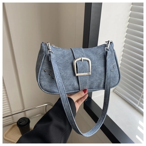 Detalle de bolso de hombro azul con hebilla plateada grande y remaches metálicos