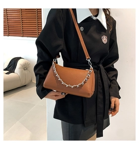 Detail of caramel brown leather crossbody bag with silver chain strap on model