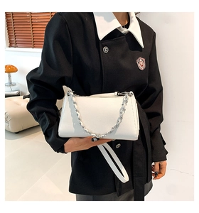Detail of white textured leather crossbody bag with silver chain and strap on hand