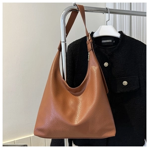 Detail of brown lychee texture leather tote bag hanging next to a tweed jacket