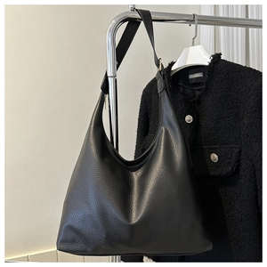 Detail of black large capacity hobo bag with litchi grain texture hanging on hanger