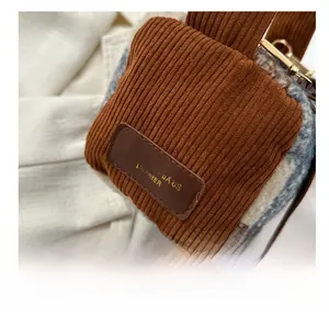 Detail der Boston-Tasche aus Tweed und Cord mit Lederetikett und goldener Schnalle