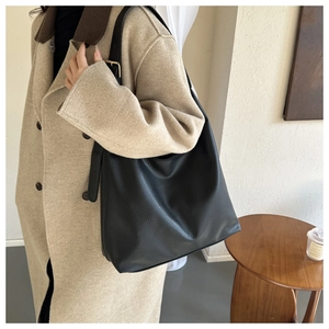 Detailed shot of a black pebbled leather tote bag with gold adjustable buckle on the strap