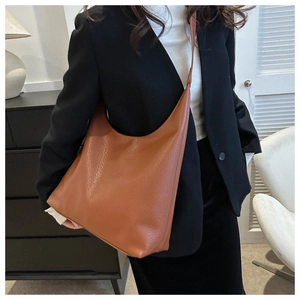 Detail of large brown hobo tote bag with lychee texture on model in black suit