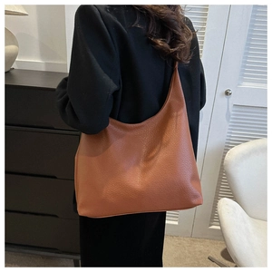 Close-up of textured brown leather tote bag showing spacious design on shoulder
