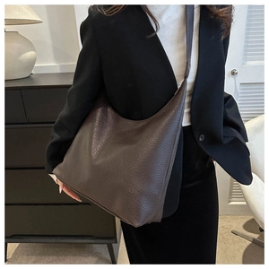 Detailed view of deep brown pebbled leather crescent tote bag worn by a model