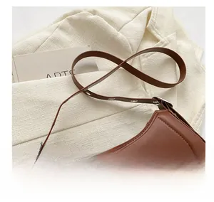 Détail d'un sac à bandoulière en cuir marron foncé avec œillets et lettrage de mode