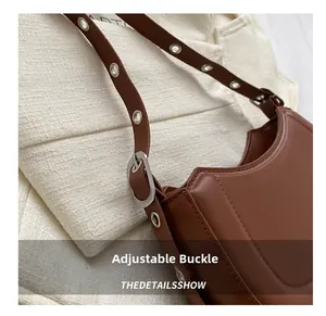 Détail de la bandoulière réglable avec boucles en métal sur le sac à main en cuir marron