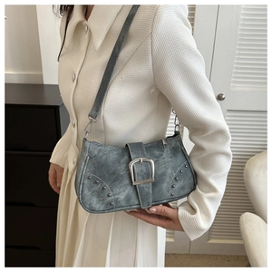 Detalle del bolso baguette vintage gris con hebilla metálica grande y remaches