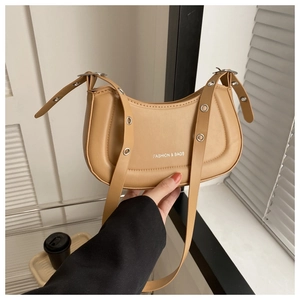 Détail du sac demi-lune marron clair avec bandoulière à œillets et logo blanc