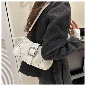 Primer plano de un bolso de hombro vintage blanco con hebilla plateada y remaches en blazer