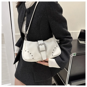 Detalle de bolso blanco de hombro con hebilla plateada grande y remaches metálicos