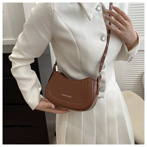 Sac bandoulière demi-lune en cuir marron avec lettrage blanc porté par un mannequin