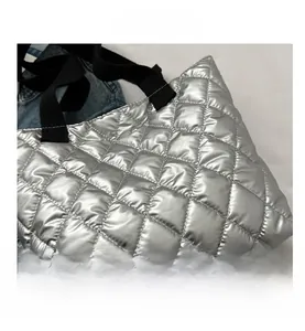 Detail view of silver quilted tote bag with black strap and metallic gloss texture