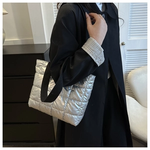 Silver quilted tote bag with metallic finish and black wide strap shown on shoulder