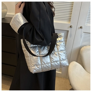 Detailed side view of silver quilted tote bag with black canvas straps on model