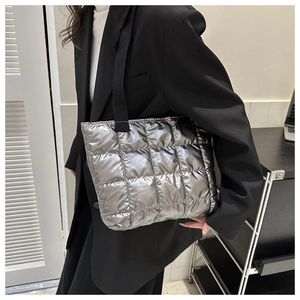 Silver quilted tote bag with metallic finish and wide black canvas shoulder strap detail