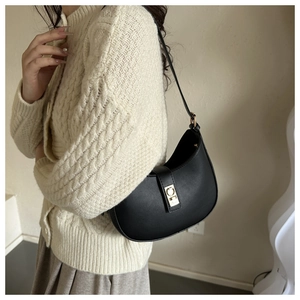 Detail of a vintage black crescent underarm bag with gold buckle on a stylish model